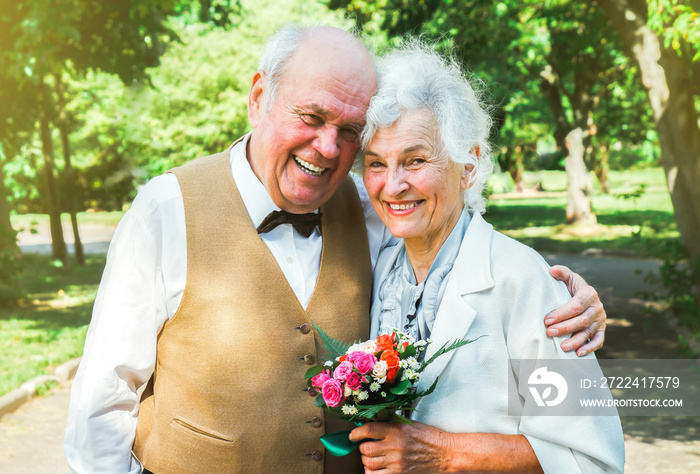 Happy senior couple love story. Old couple is walking in the green park. Grandmother and grandfather laughing. Elderly people lifestyle. Together Pensioners.