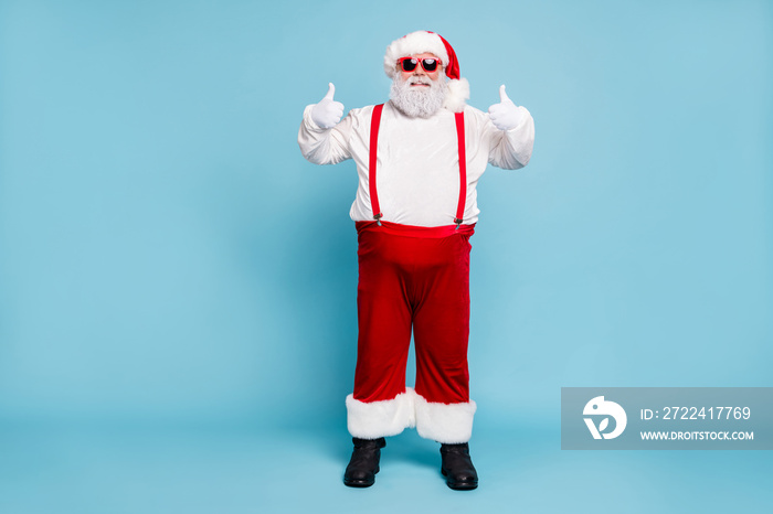 Full body photo of funny funky fat santa claus with big belly abdomen in eyewear show thumb up recommend winter season shopping ads wear red overalls boots pants isolated over blue color background