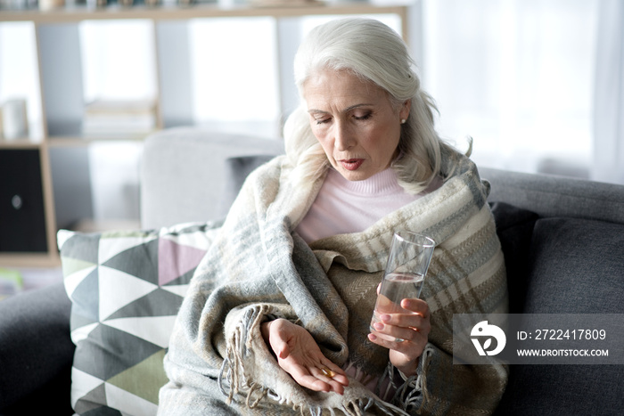 Sick mature lady curing herself by medication