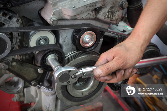 Worker fixing pk belt, pulleys and alternator at modern car engine, closeup of hands and tool