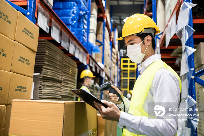 Asian male engineer worker wear mask work during COVID in warehouse.