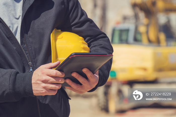 Builder with digital tablet posing on a heavy construction site.