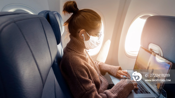 A young woman wearing face mask is traveling on airplane , New normal travel after covid-19 pandemic concept