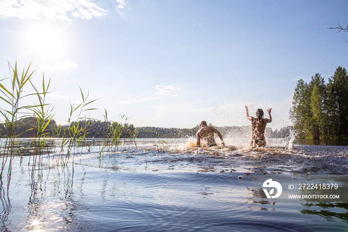 Man and a woman bathe, splash and have fun in a clean forest lake on a hot summer day. Active tourist life.