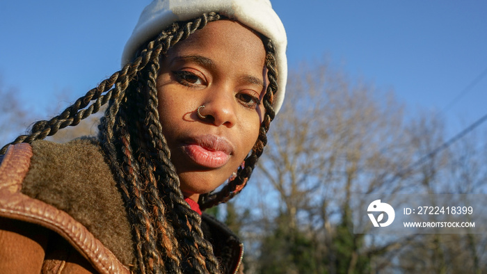 Portrait of young woman with braided hair and cap outdoors