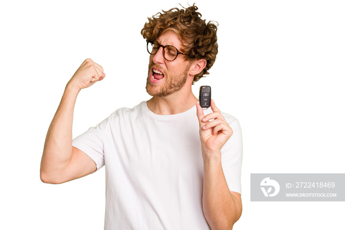 Young caucasian man holding car keys isolated on white background raising fist after a victory, winner concept.