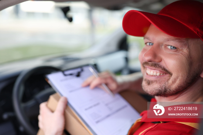 Portrait of smiling male courier driver in car salon with documents