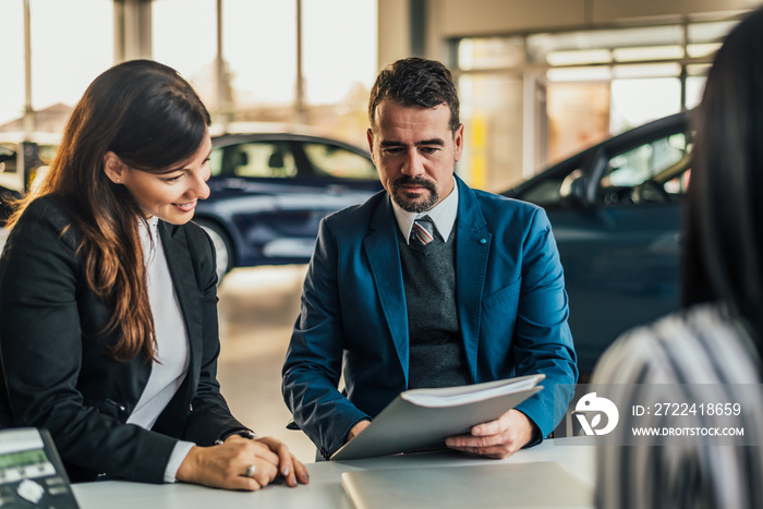 Mature car dealer showing contract to client.