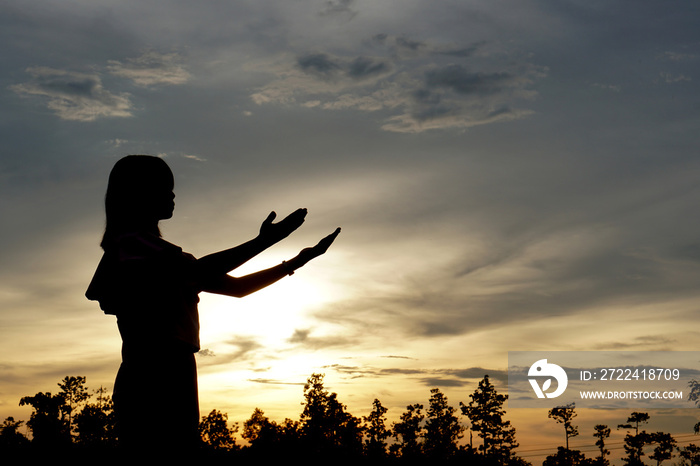 silhouette of a woman asking for blessings from God Evening sun background