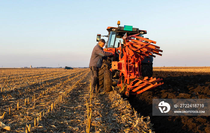 mechanic fixing plow on the tractor