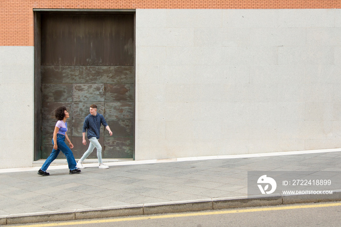 couple white man and black woman walking having fun and laughing 20s