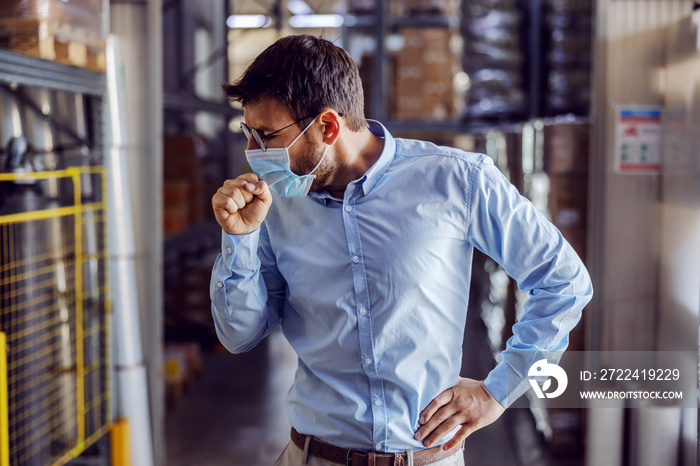 Full length of handsome smiling businessman having phone call with customer while walking in warehouse.