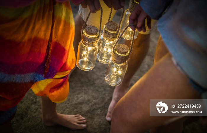 Hipster friends having fun together at beach camping party - Friendship travel concept with young people holding neon led lanterns at summer sea camp - High iso image with night dark vignetting filter