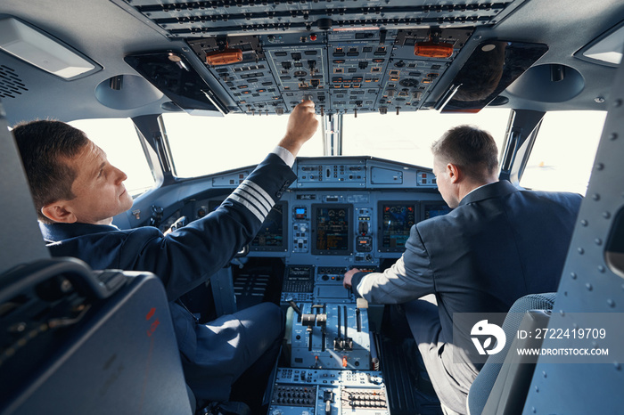 Pair of aircraft pilots toggling switches while taking-off