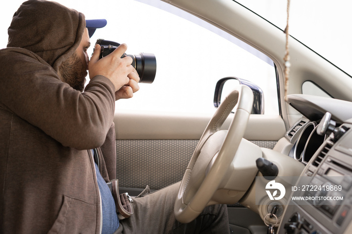 Private detective sitting inside a car photographing with a professional camera