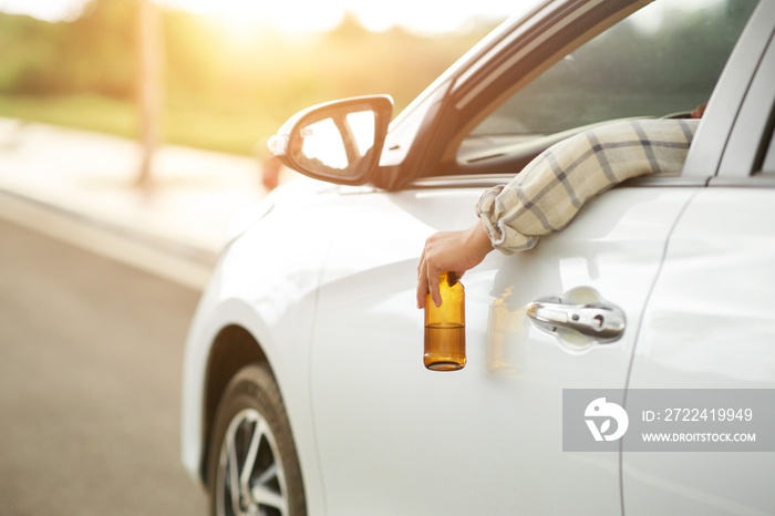 Drunk man holding bottle of beer while driving a car, campaigning for drunken not driving avoiding accidents on road, Don’t drink and drive concept.