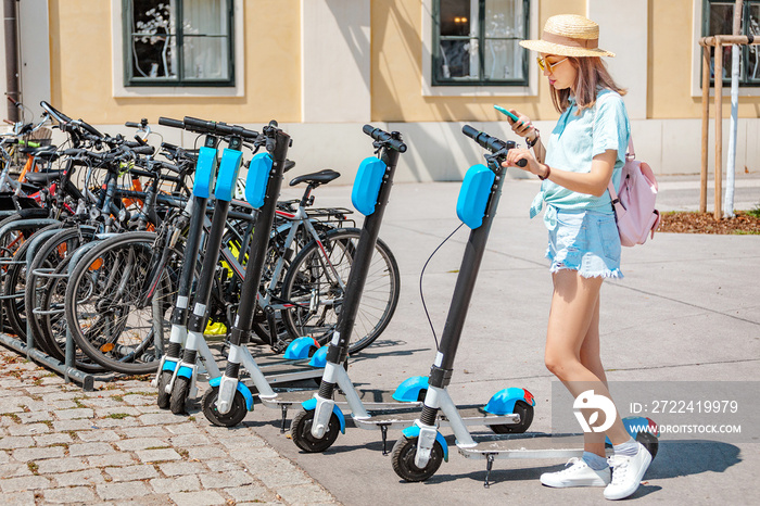 Asian woman renting electric kick scooter at city street. Modern sharing urban transport concept