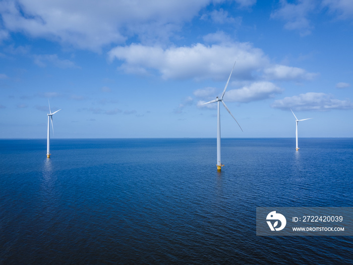 offshore windmill park with clouds and a blue sky, windmill park in the ocean aerial view with wind turbine Flevoland Netherlands Ijsselmeer. Green energy