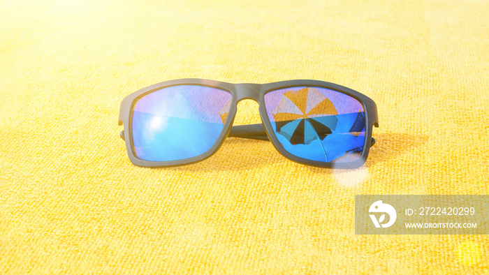 Sunglasses closeup summer background. Beach pool equipment with travel sunglasses on yellow holiday towel. Outdoor relax holiday at ocean.