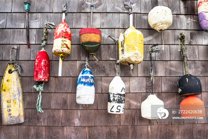 Close up of old lobster buoys hanging on a weathered wooden exterior wall of a fishing hut