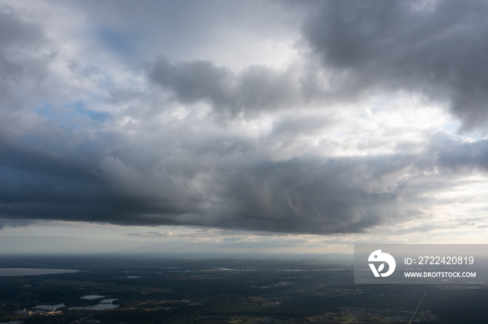 a view of a cloudy sky with a plane in the foreground and a body of water in the distance in the foreground, and a city in the distance, with a few clouds in the foreground. .