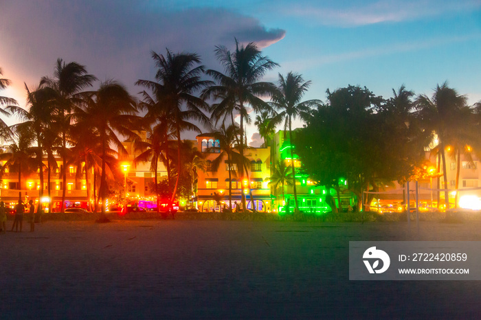 Miami Beach Ocean Drive hotels and restaurants at sunset. City skyline with palm trees at night. Art deco nightlife on South beach