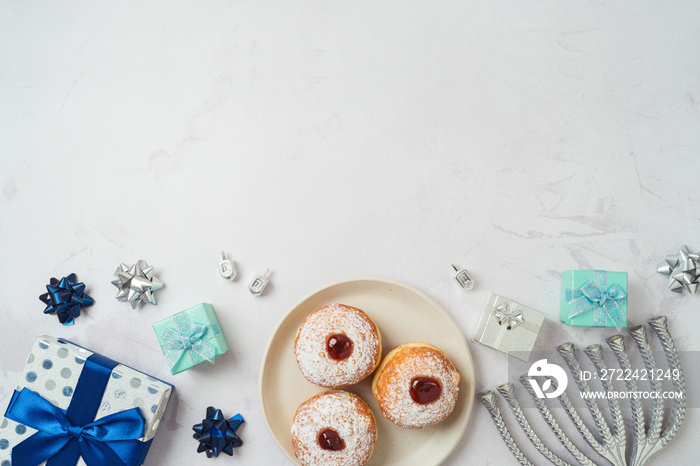 Jewish holiday Hanukkah background with traditional donuts, menorah and gift box. Top view, flat lay