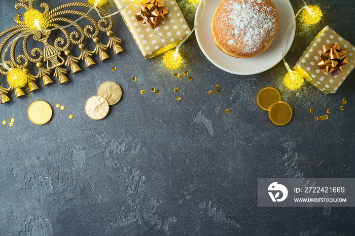 Jewish holiday Hanukkah concept with traditional donuts, menorah and gift box on dark background. Top view with copy space