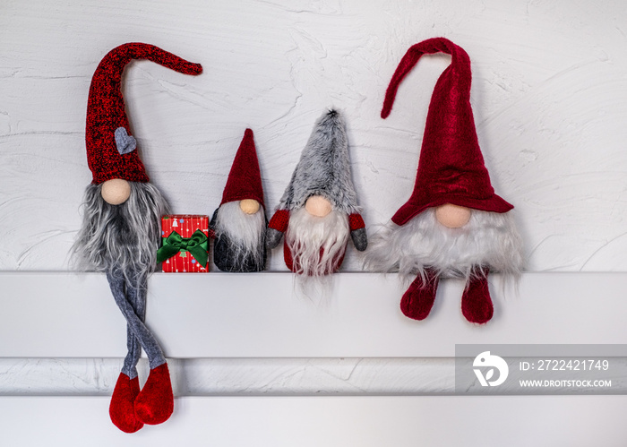 Cute Christmas gnomes. Christmas Elves decorations. Four dwarves with Christmas holiday present is sitting on a wooden shelf. Christmas and New Year concept, greeting card