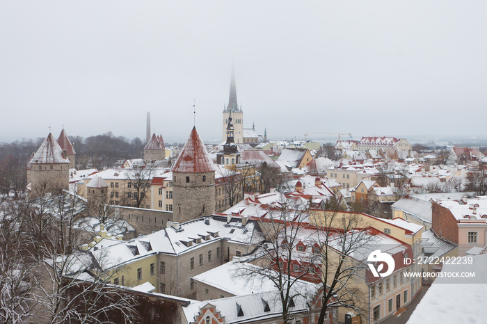 Tower of the city wall and Oleviste Catholic Church at the Old city of Tallinn in Estonia at the winter time. Gothic Scandinavian architecture of medieval charming city of Tallinn Old Town and snow.