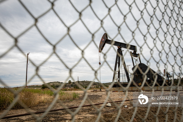 Oil Pump in Cloudy Rough Weather with Chain Link Fence