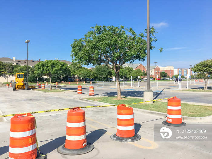 Uncover parking garage lots remodel in progress at wholesale retail store in Lewisville, Texas, US. Row of plastic cones adapters chain barrier and heavy construction equipments, industrial background