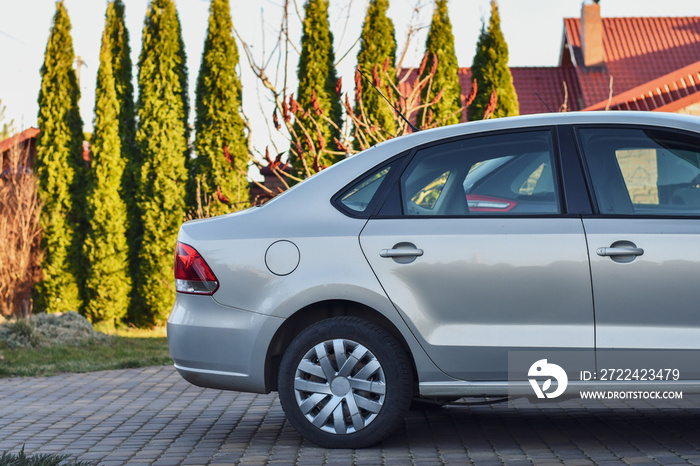 Back part of the car parked near the garage on the background of garden.