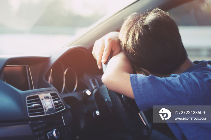 Drunk young man slumped on steering wheel be tired sleep in car driving. concept sleepy while driving travel, do not drive. It can be dangerous.