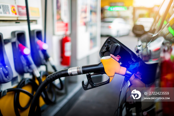 Hand refilling the white pickup truck with fuel at the gas station.