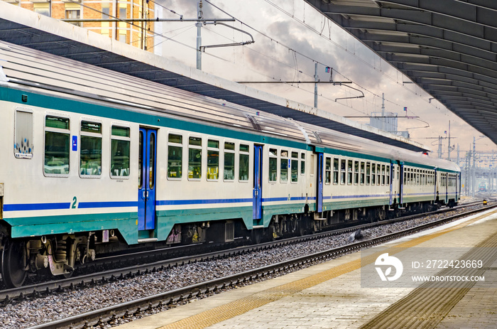 Beautiful railway station with modern red commuter train at colorful sunset in Venice, Italy. Railroad with vintage toning