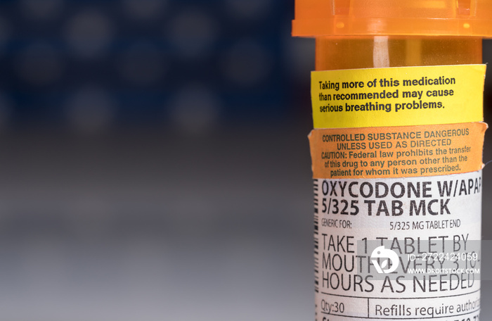 Oxycodone is the generic name for a range of opoid pain killing tablets. Prescription bottle for Oxycodone tablets and pills with USA flag in background