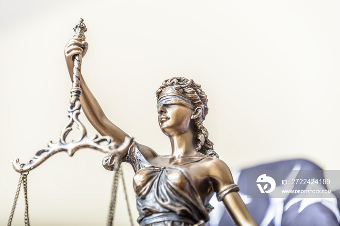 The statue of justice Themis or Iustitia, the goddess of justice blindfolded against a flag of the United States of America, as a legal concept.