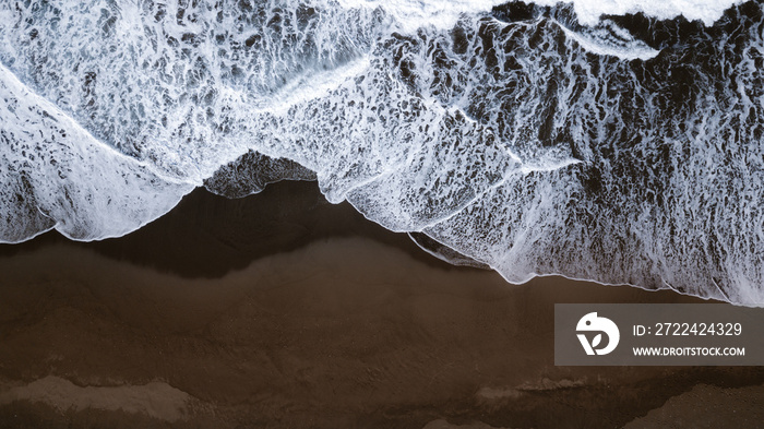 imagen cenital de una playa de arena negra y olas