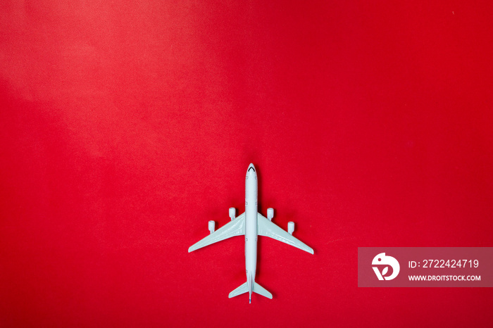 Miniature toy airplane on red background. Trip by airplane.