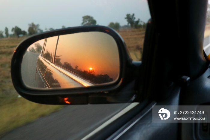 Beautiful view of morning sunlight reflection in sideview mirror of car on country road. Transportation, journey and travel concept.