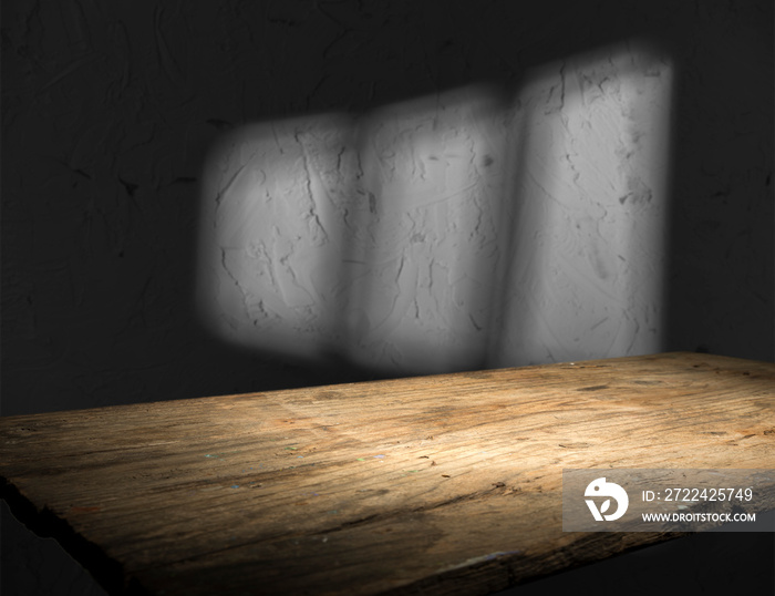 Old wood table with blurred concrete block wall in dark room background.