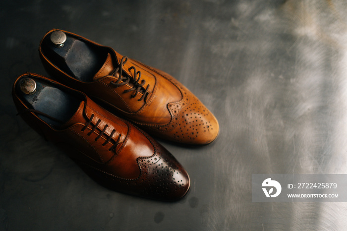 Close-up top view of old light brown leather shoe and repaired shiny shoes after restoration working. Concept of cobbler artisan repairing and restoration work in shoe repair shop.