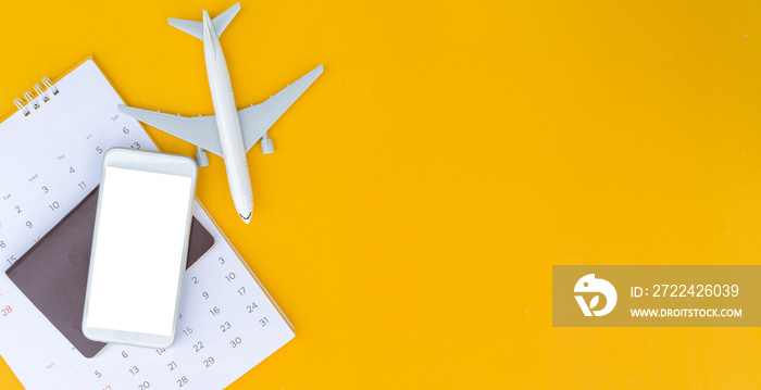 close up top view on blank smartphone with passport and calendar and airplane model on yellow color background for summer holiday lifestyle concept