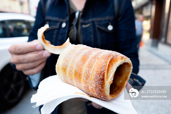 man eating a typical Czech trdelnik in Prague