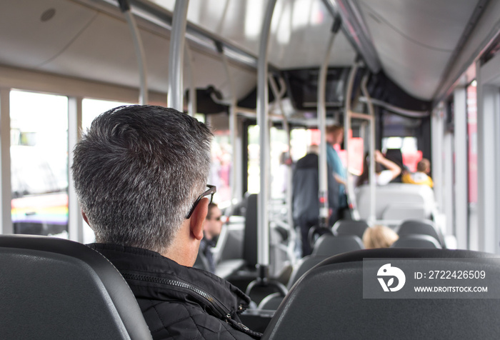 Rear view of man sitting in a seat on a public bus.  Selective focus