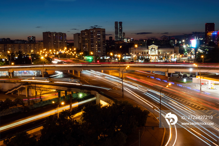 City highway traffic - street with fast moving cars and lights trails - long exposure. Warm illumination at night. Rush hour, urban, transportation and city life concept