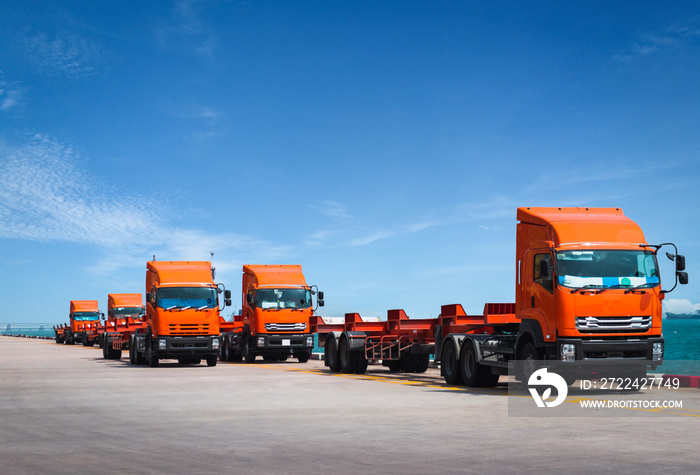 Fleet of trucks and trailer awaiting to pick containers on jetty harbor. Container transportation and logistics, trucking and delivery.