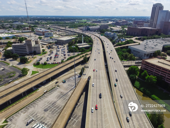 Aerial view highway I45 (Gulf Freeway), asphalt elevated road and Bayou River in downtown Houston, Texas, US. Passenger cars, trucks commuting daytime. Parking garage and office building in background