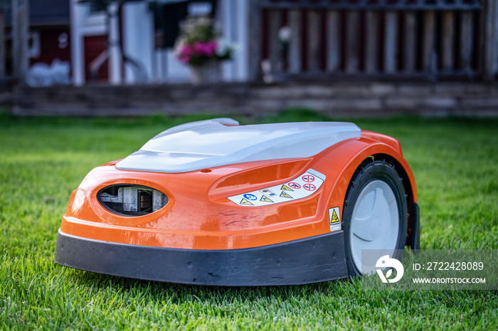 Automatic lawn robot mower moves on the grass, lawn. Close up side view with blurry background